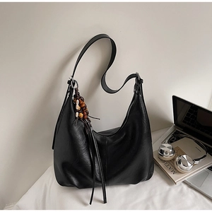 Detail view of black PU leather hobo bag with vintage wooden beads and tassel charm