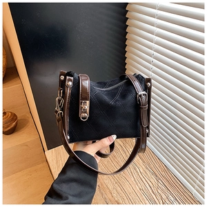 Detail of black quilted suede handbag with brown leather strap and vintage gold hardware