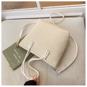 Vue détaillée de dessus du sac seau tissé beige avec poignée nouée et bandoulière