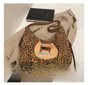 Détail du sac cabas léopard avec lanières en cuir marron et écusson de chat brodé