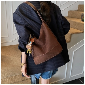Détail du sac fourre-tout en daim marron foncé avec un ours et un porte-clés en étoile
