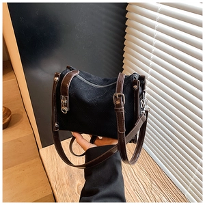 Detail of black quilted suede handbag with adjustable brown leather strap and silver hardware