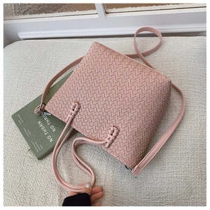 Détail du sac seau bandoulière tissé rose clair avec texture raffinée en similicuir chic