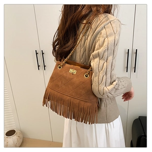 Detail of vintage brown suede bucket bag with fringe trim and golden chain strap