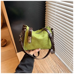 Detail of green quilted suede handbag with brown leather handle and silver lock buckle