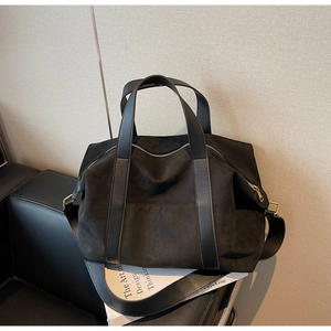 Macro shot of black suede tote bag with gold hardware and leather shoulder strap