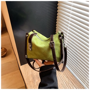 Detail of green nylon barrel bag with quilted diamond pattern and contrast brown strap