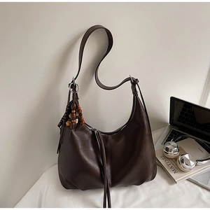 Detail of dark brown hobo bag featuring silver zipper and vintage wooden bead charm