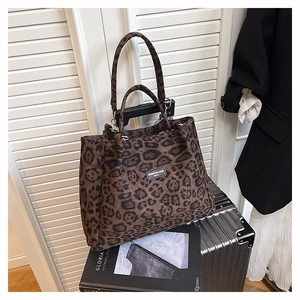 Detail of leopard print tote bag with dual straps placed on a silver suitcase
