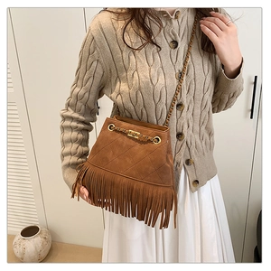 Close-up of brown suede tassel bucket bag with gold chain strap and quilted texture