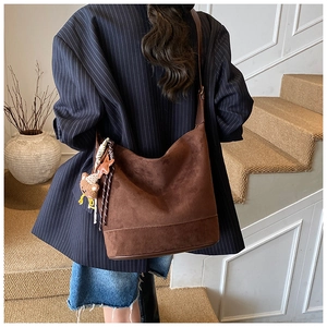 Sac hobo en daim marron avec pendentif ours et gland étoile porté par un mannequin
