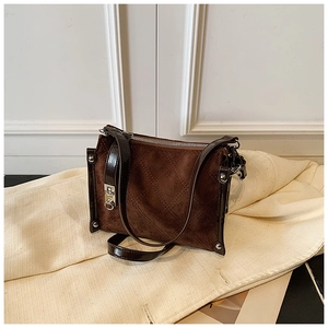 Close-up of brown suede bag with quilted diamond pattern and metallic twist lock closure