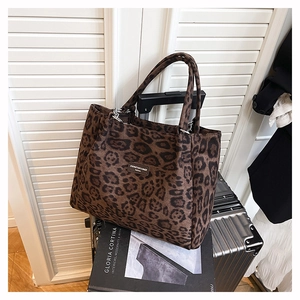 Detail of leopard print tote bag with metal rings and logo on luggage and book