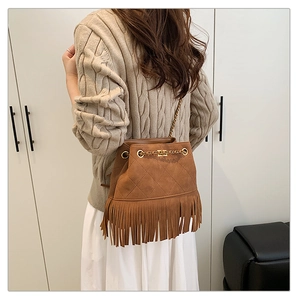 Close-up of brown suede bucket bag with long fringe tassels and quilted diamond pattern