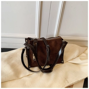 Close-up of brown suede square handbag with decorative stitching and metal zipper detail