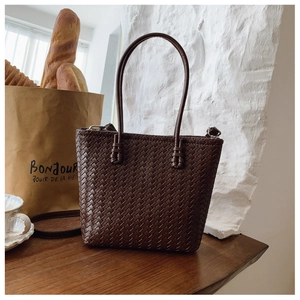 Détail de la texture tressée marron foncé d'un grand sac cabas avec boucles argentées