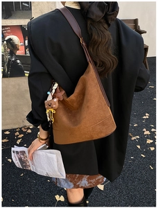Détail du grand sac cabas en daim marron foncé avec pendentif ours dans un décor de rue