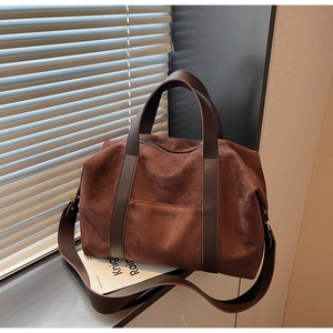 Close-up of brown suede tote bag with leather handles and metallic zipper detail