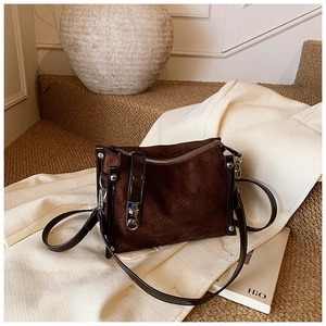 Detail of dark brown suede crossbody bag with elegant diamond quilted stitching and metal clasp