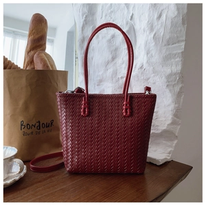 Détail du cuir tressé bordeaux sur un grand sac seau avec bandoulière et poignées