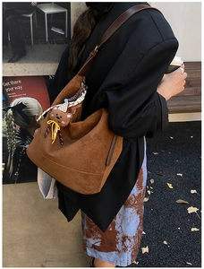 Détail du sac hobo en daim marron avec un pendentif ours et un foulard en soie à pois