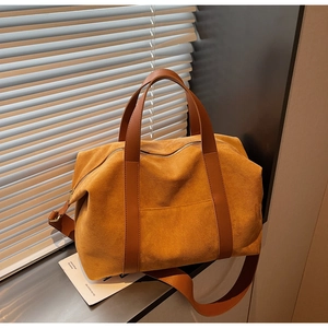 Detail of a large orange suede tote bag with leather handles and zip closure