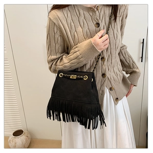 Close-up of black fringe bucket bag with gold chain strap and suede-like texture