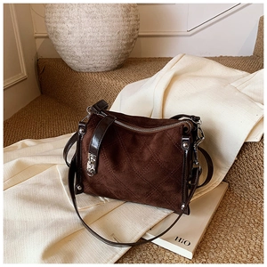 Detailed macro view of dark brown suede crossbody bag with elegant diamond quilted stitching