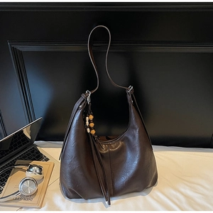 Detailed close-up of dark brown hobo bag with vintage beaded tassel and oil-glossy finish