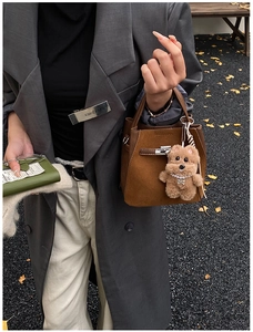 Dettaglio di borsa tote in pelle scamosciata marrone con ciondolo a forma di cane di peluche