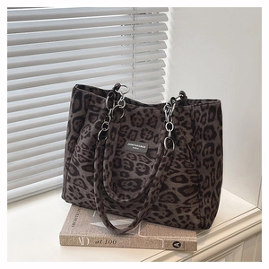 Detail of leopard print tote bag featuring silver chain handle and metallic logo plaque