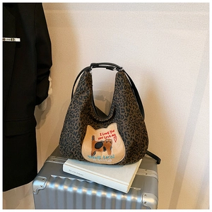 Détail du sac fourre-tout léopard avec un écusson de chat et une bandoulière noire