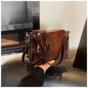 Close-up of brown suede crossbody bag with quilted stitching and faux leather trim