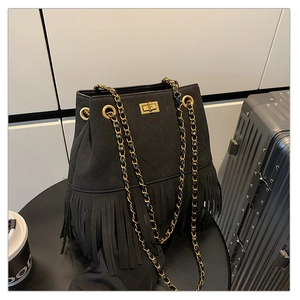 Detail of black quilted bucket bag with long tassels and gold metal chain strap