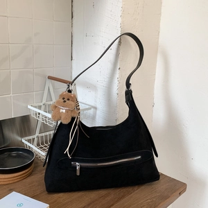 Détail du sac hobo en daim noir avec poche zippée et pendentif ours en peluche marron