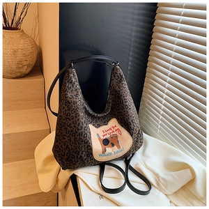 Détail du sac hobo léopard avec écusson chat brodé et bandoulière en cuir noir