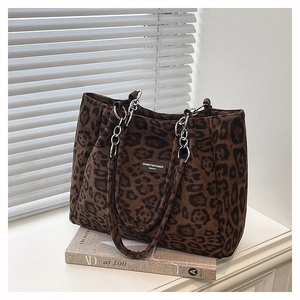 Detail of leopard print tote bag with metal chain strap and logo on faux suede texture