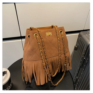 Macro shot of caramel brown suede bucket bag with long fringe and gold chain strap