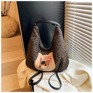 Détail du sac cabas en toile léopard avec écusson de chat et bandoulières en cuir