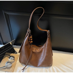 Detail of vintage brown leather hobo bag with wood bead tassel and zipper closure