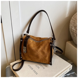 Detail of tan suede quilted barrel bag with dark brown leather straps and silver hardware