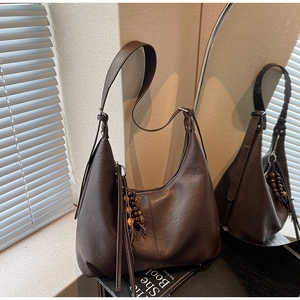 Macro view of dark brown faux leather bag featuring ethnic wood bead tassel details