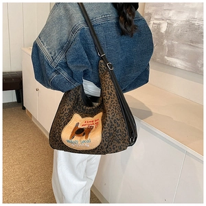 Détail du sac léopard avec broderie de chat et bandoulière noire réglable sur l'épaule