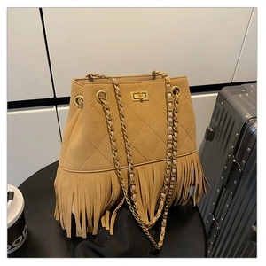 Close-up of mustard yellow suede bucket bag with fringe tassels and diamond quilting