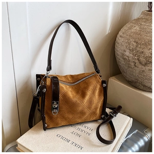 Close-up of brown suede crossbody bag with elegant diamond quilted stitching detail