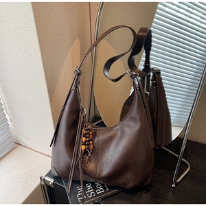 Detail of dark brown leather Hobo bag featuring wooden bead tassel and silver zipper