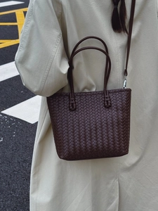 Sac seau en cuir tressé marron foncé avec détails argentés sur un mannequin