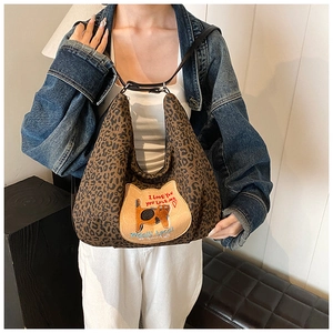 Détail du sac hobo léopard avec un écusson de chat brodé et un slogan élégant