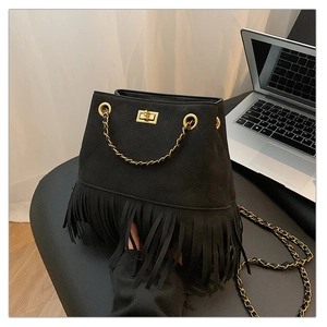 Detail of black quilted suede bucket bag with gold clasp and long fringe tassels