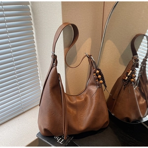 Detail of brown faux leather shoulder bag with vintage tassels and wooden bead charm